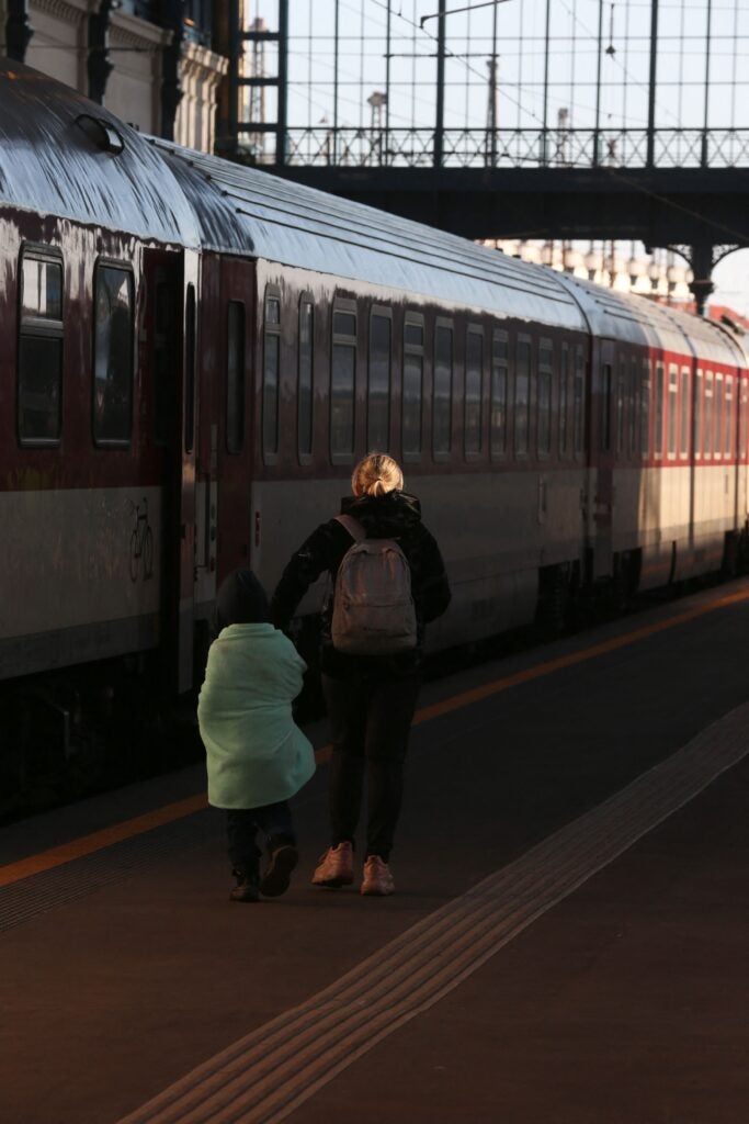 An Ukranian refugee with her son waits for a train to the Czech capital Prague in Budapest on March 1, 2022. - Mostly foreign students from Ukraine arrive to the Westend railway station in Budapest and want to head to other countries. (Photo by FERENC ISZA / AFP) (Photo by FERENC ISZA/AFP via Getty Images)