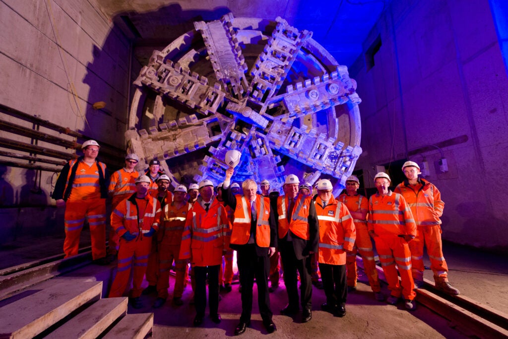 Londono meras Borisas Johnsonas stovi su Crossrail darbuotojais prie vienos iš 1000 tonų sveriančių tunelių gręžimo staklių Londone.