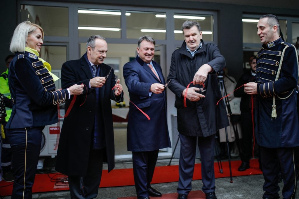 A group of people cutting a ribbon in front of a building